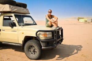 woman sitting on top of the hood of a truck smiling.