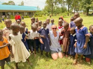 Woman standing among many school aged children in Kenya .